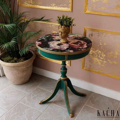 Decorative round table with floral design and gold accents in a room with framed artwork and a plant.